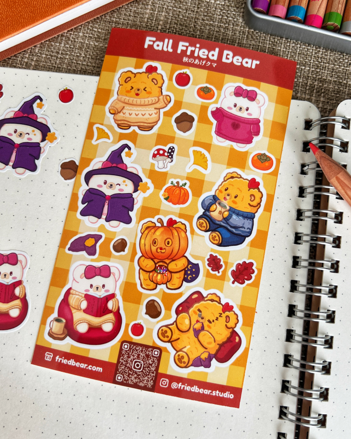 Fall Fried Bear sticker sheet with pumpkins, sweaters and a witch hat lying on a dotted notebook